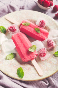Homemade raspberry popsicles on plate with ice and berries. Summer food concept.